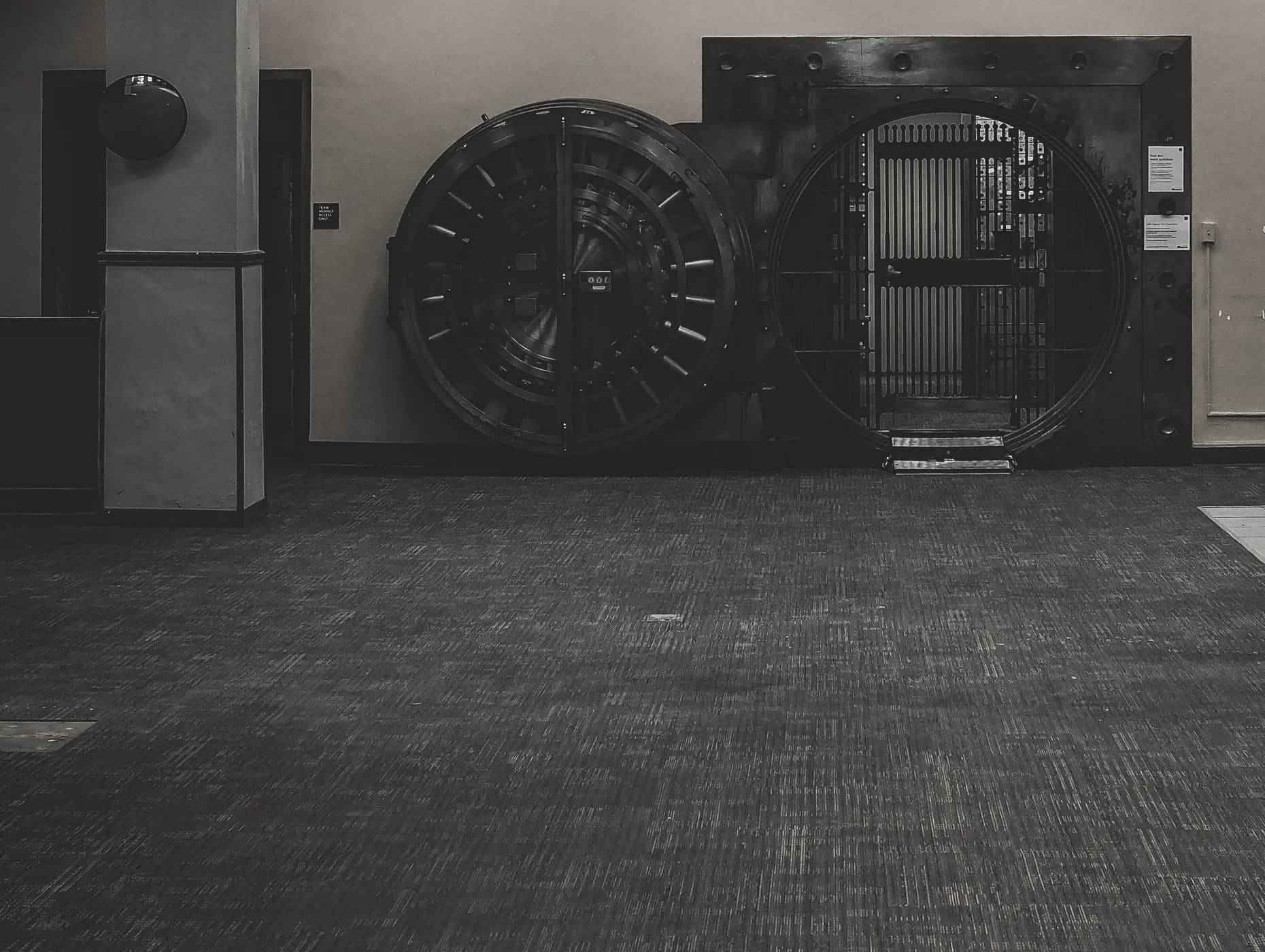 A working strongroom with two circular steel vault doors standing open on an empty floor.